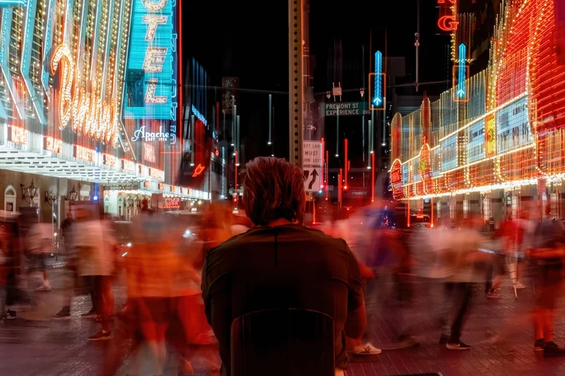 Man stands in a busy, brightly lit street at night.
